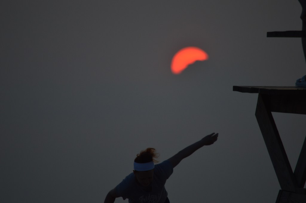 Silhouette of a person reaching up toward a red sun