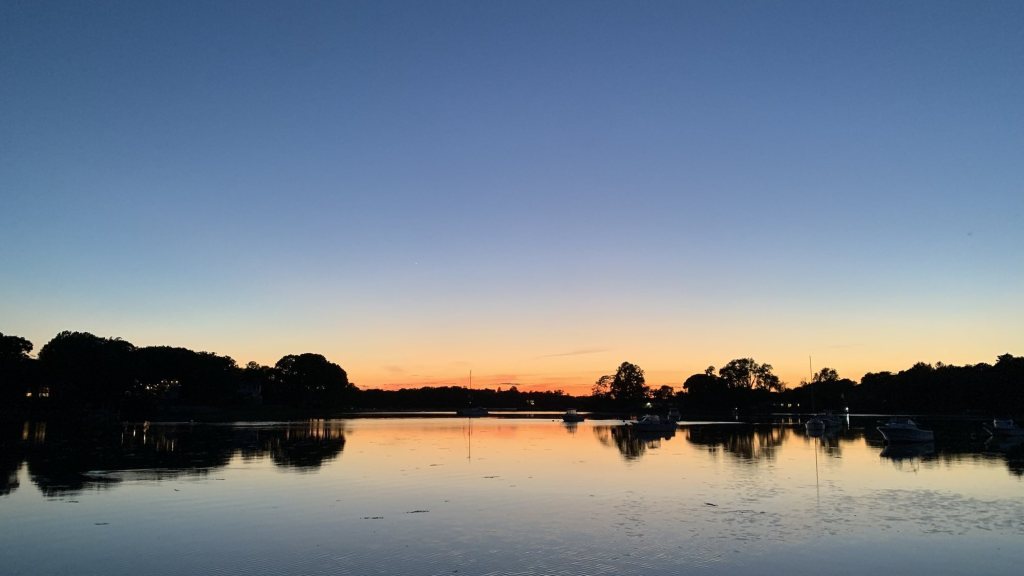 Orange glow on the horizon over a calm harbor after sunset