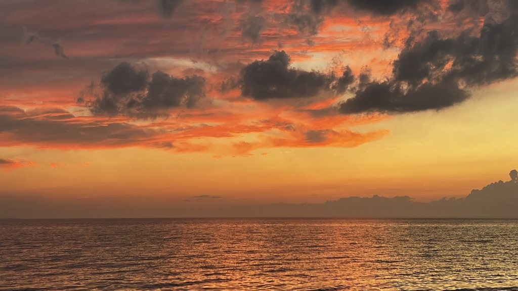Orange sunset clouds over open water